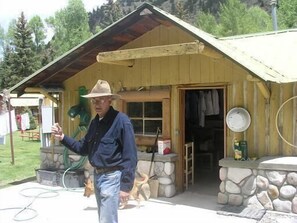 A rustic cabin with a stone foundation, a wooden door, and a metal roof.