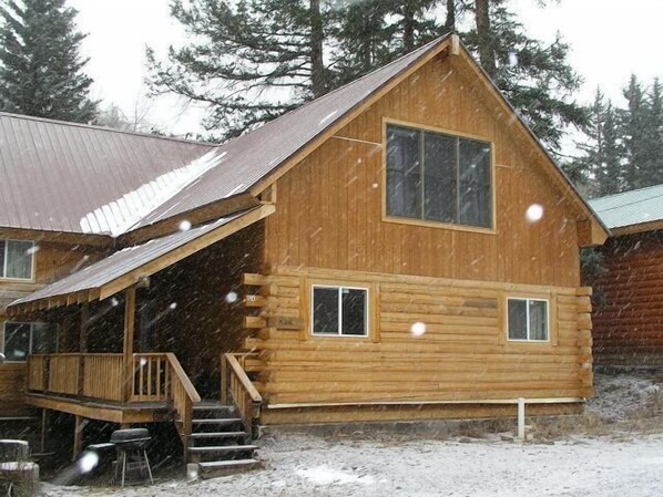 A log cabin with a porch, a staircase, and a window.