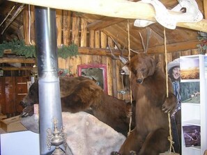 A rustic interior with wooden walls, a metal column, and a bear sculpture.
