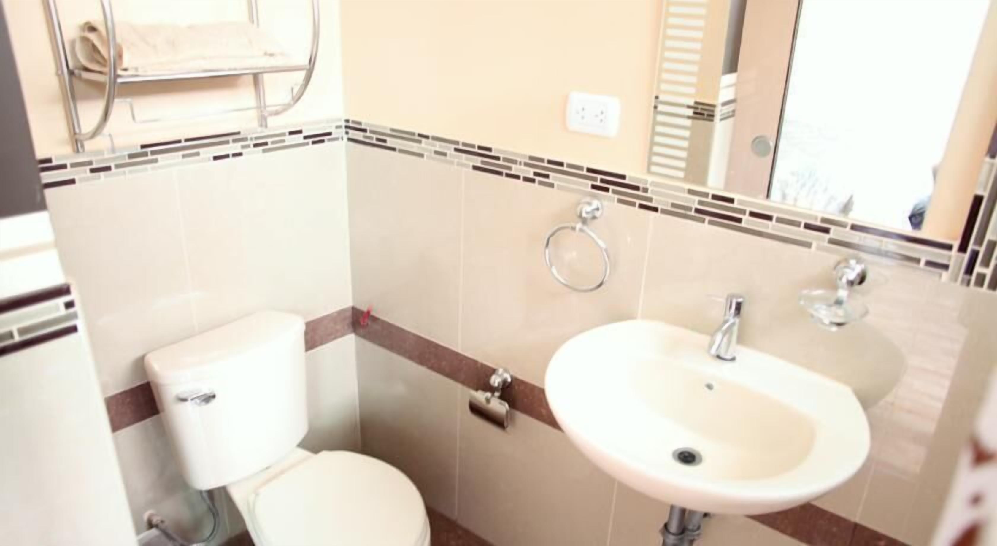 A bathroom with a toilet, sink, and towel rack.