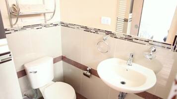 Un baño con inodoro, lavamanos y toallero.