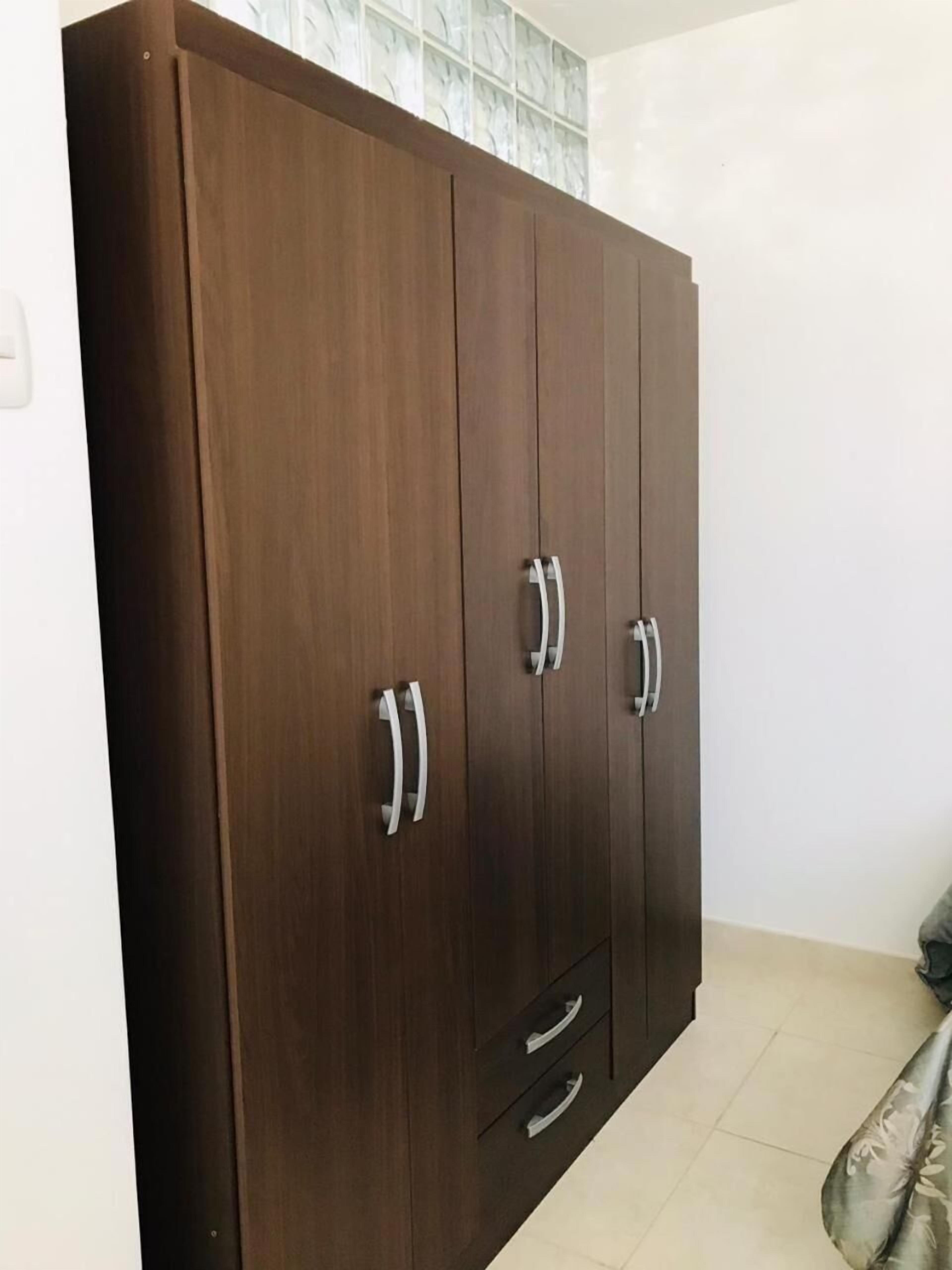 A large wooden wardrobe with two drawers and two doors, featuring silver handles.