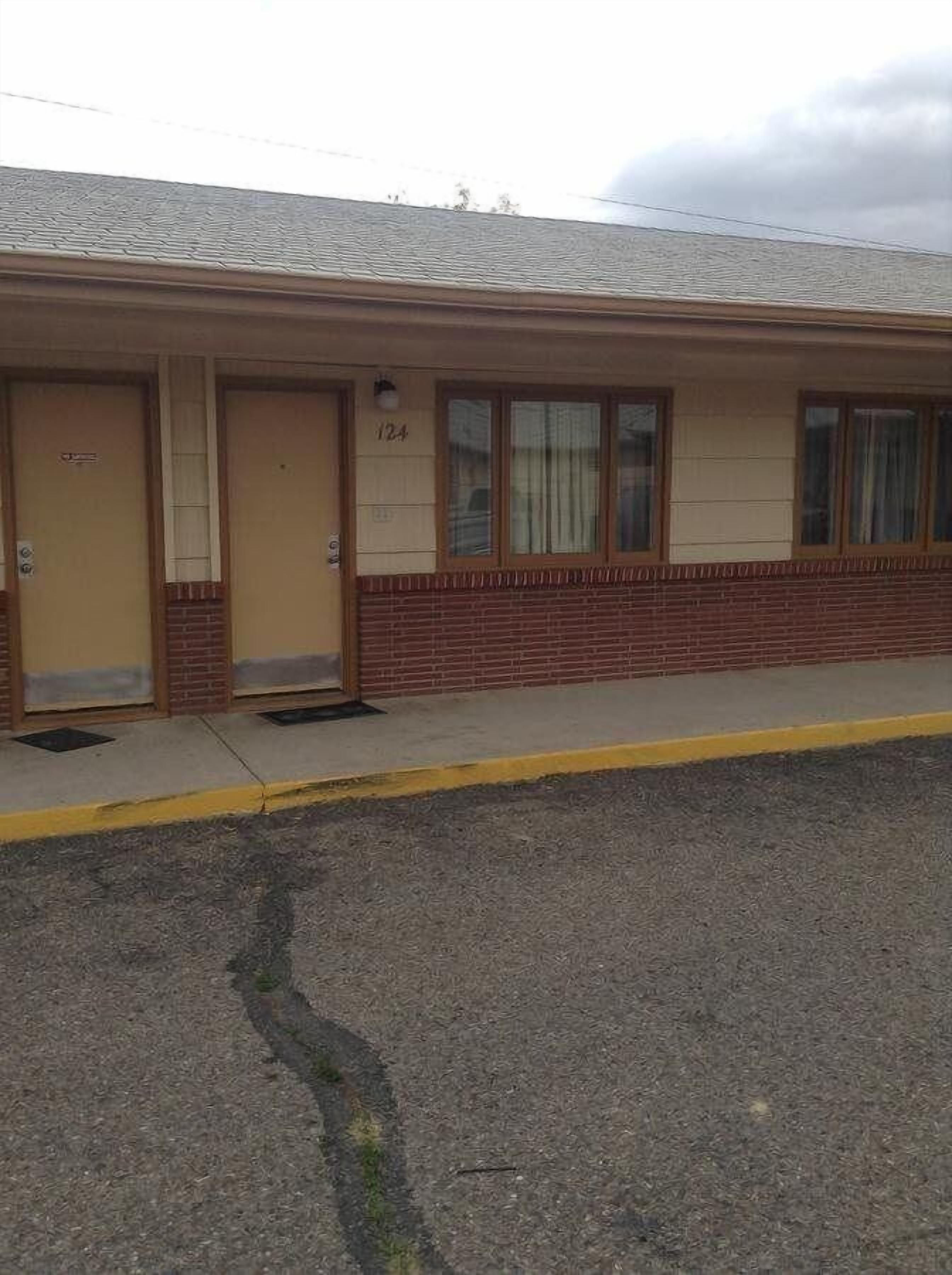 A building with numbered doors, a brick lower section, and a flat roof.