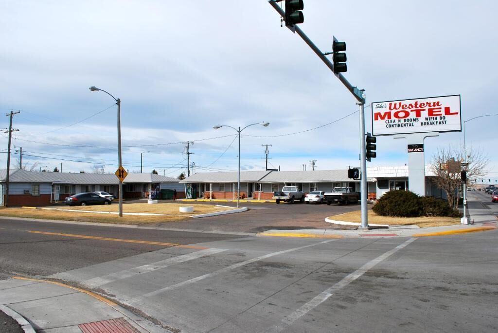 Un motel de style occidental offrant une vue dégagée sur l’immeuble et un parking.