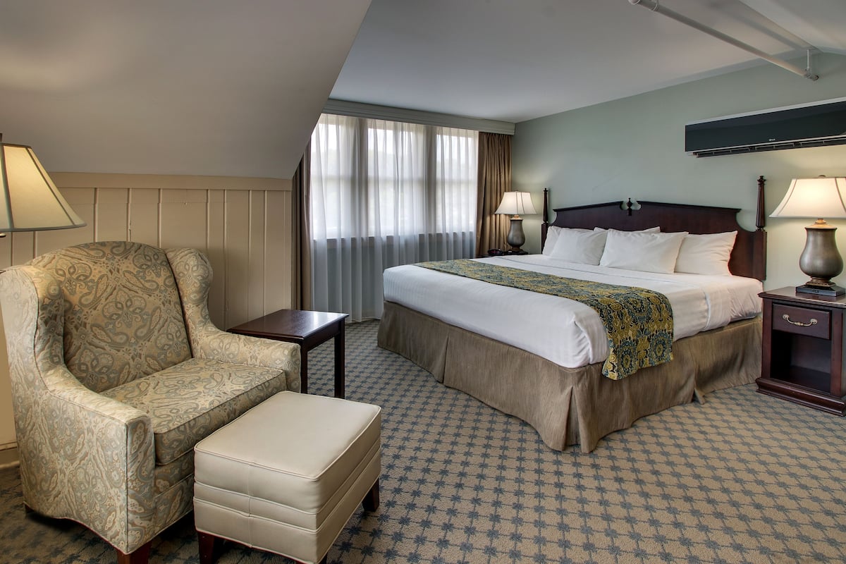 A hotel room with a bed, a chair, a small table, and a nightstand.
