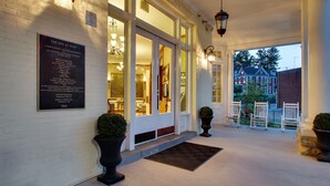 A hotel entrance with a plaque, large windows, and a covered porch with chairs. - The Inn at Wise (Wise)