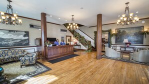 A lobby with a wooden floor, a reception desk, a staircase, and a large painting on the wall. - The Inn at Wise (Wise)