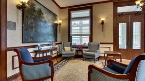 A lobby with a large painting, two armchairs, a small table, and a notice board. - The Inn at Wise (Wise)