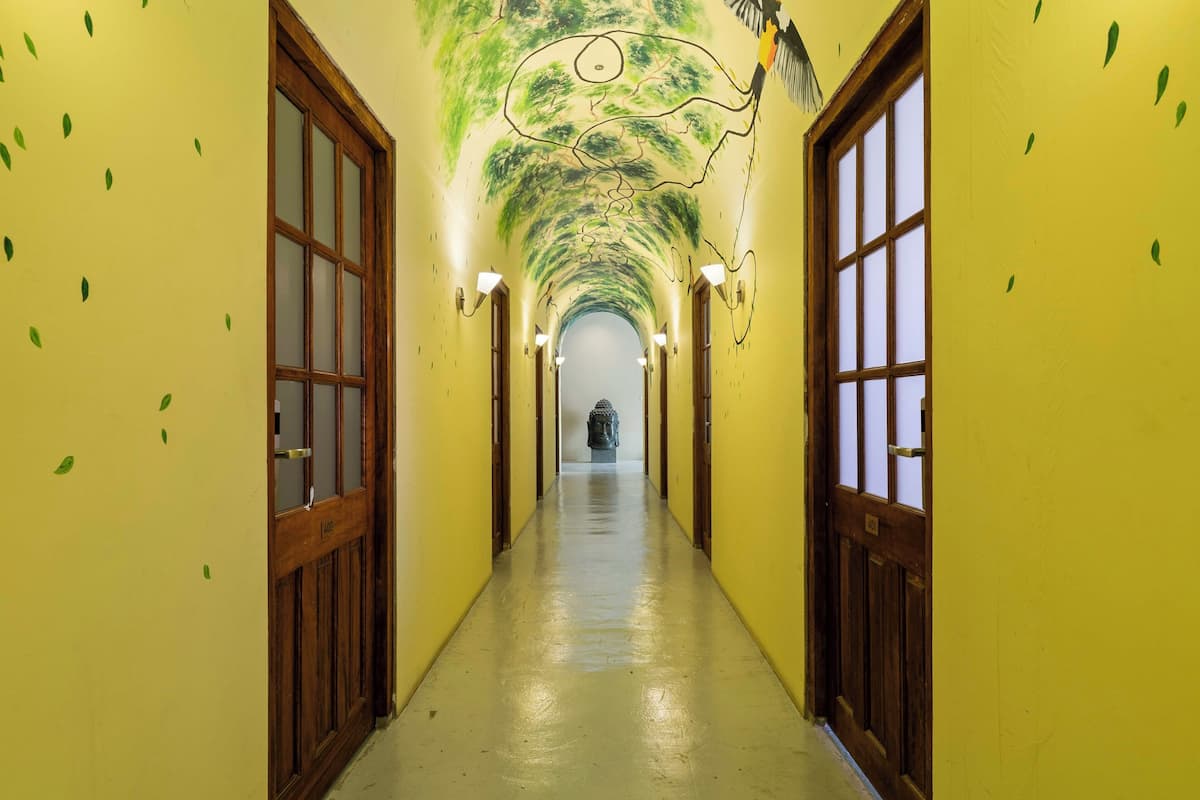 A hallway with yellow walls, wooden doors, and a mural on the ceiling.