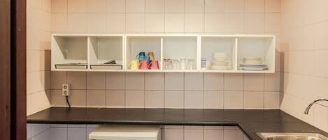 A kitchen with white cabinets, a black countertop, a dishwasher, and a stainless steel sink.