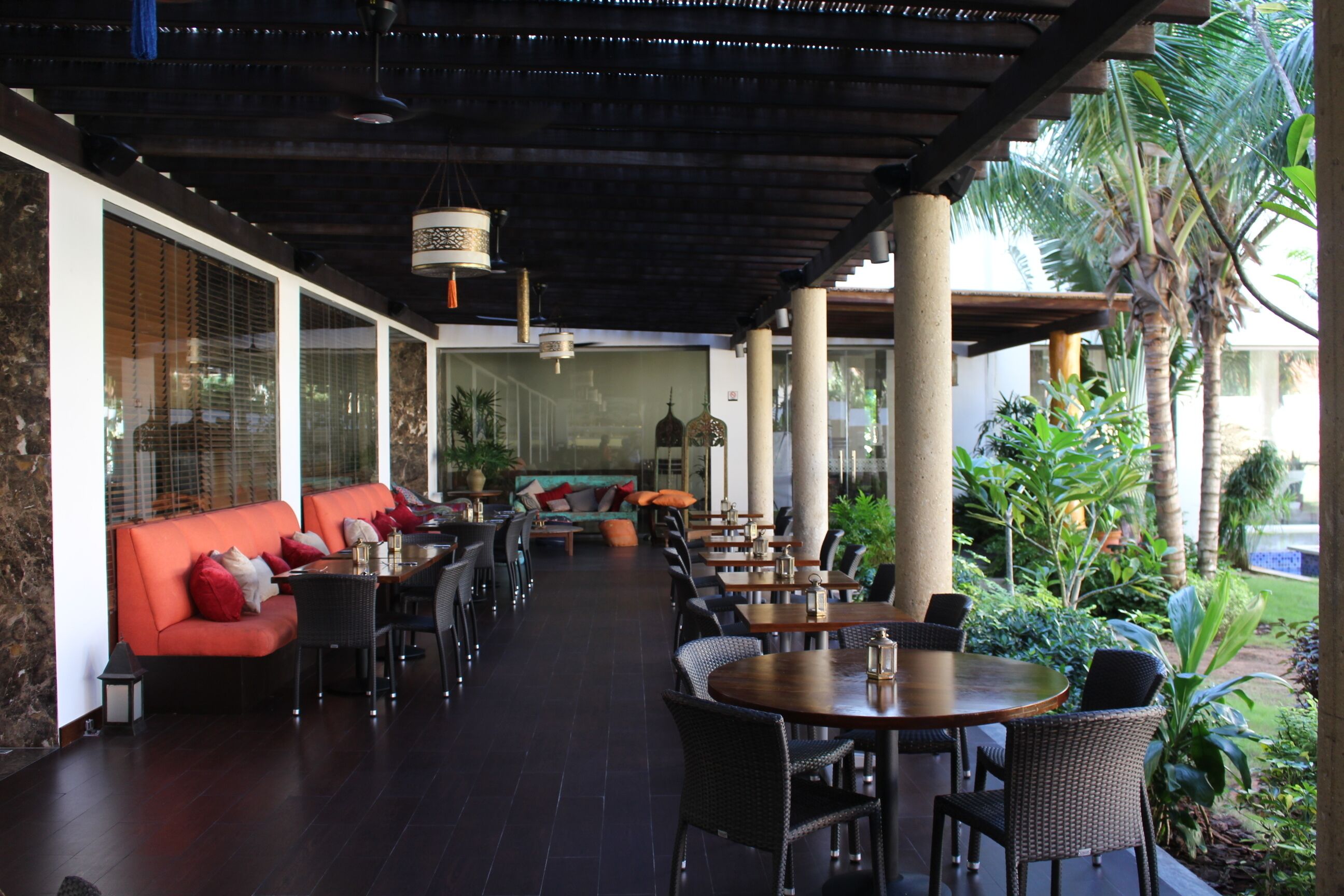 An outdoor dining area with a covered patio, seating arrangements, and a view of the surrounding greenery.