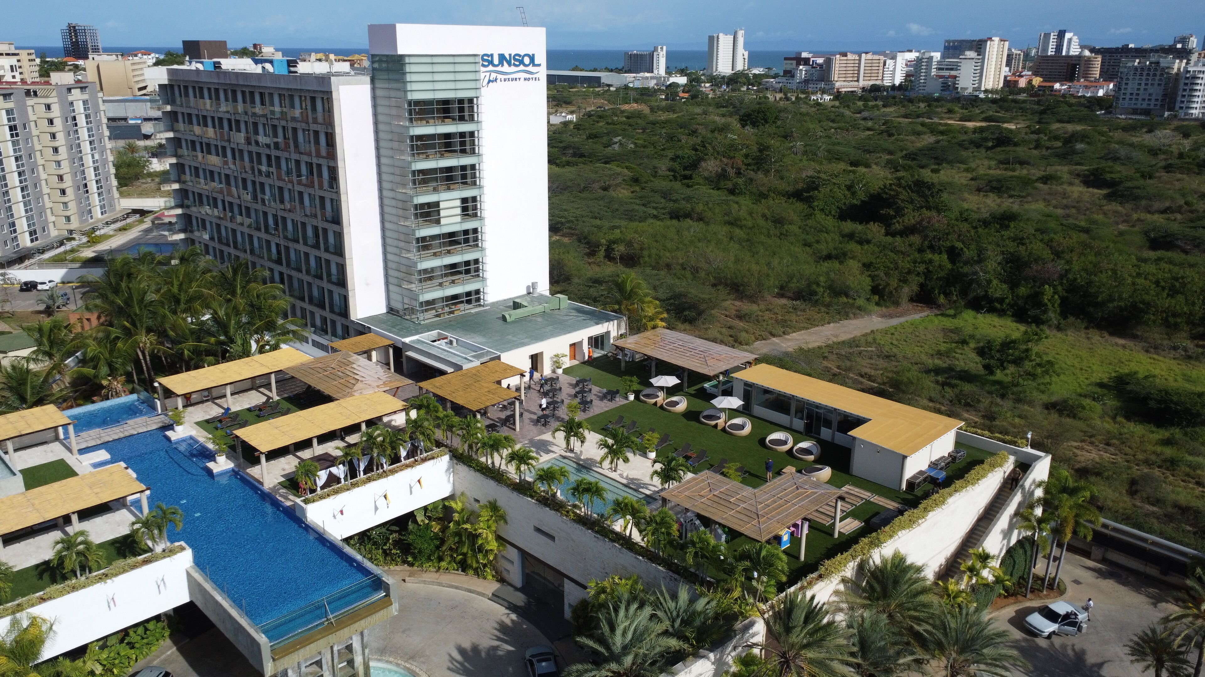A modern hotel with a rooftop pool, multiple dining areas, and a view of the city skyline.