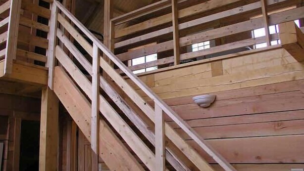 Puinen portaikko, jossa on kaide, johtaa toisen kerroksen parvekkeelle.