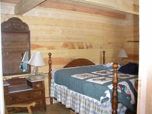 A wooden room with a bed, a dresser, and a mirror.