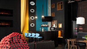 A modern bar area with a counter, bar stools, and a seating area with a red net-like structure. - Alt Hotel Winnipeg (Winnipeg)