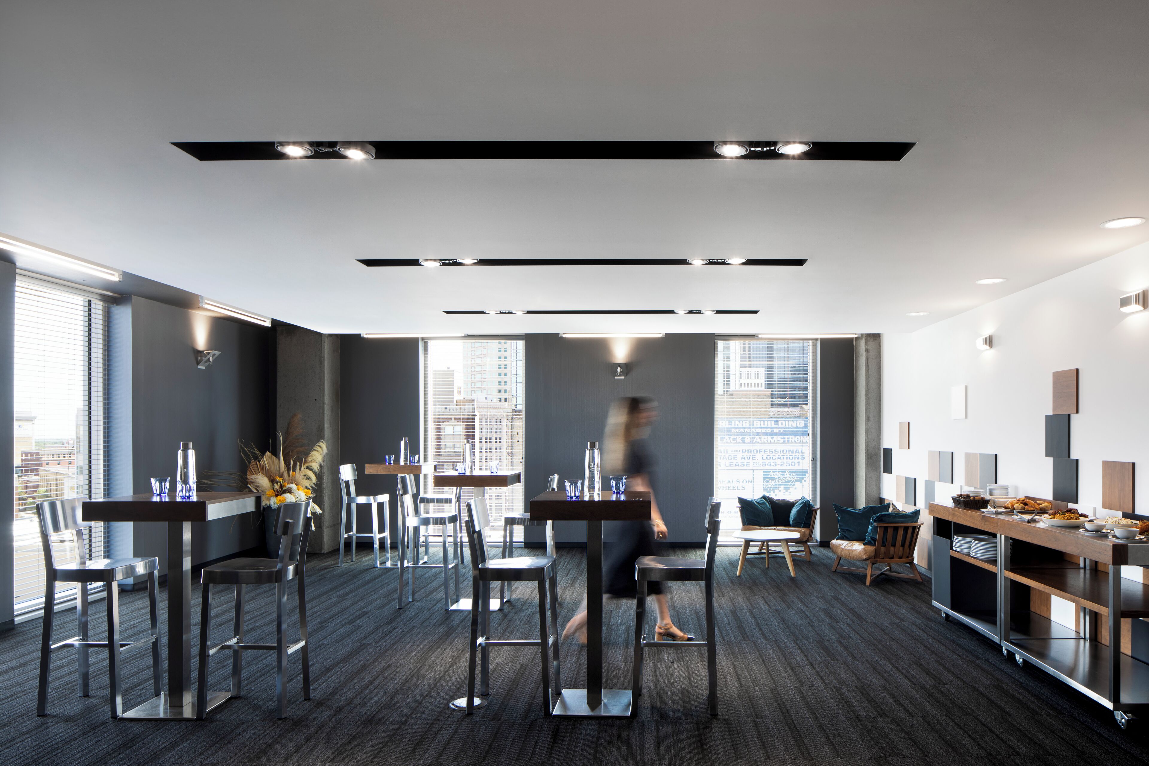 Un espacio de oficina moderno con comedor, ventanas amplias y vistas a la ciudad.