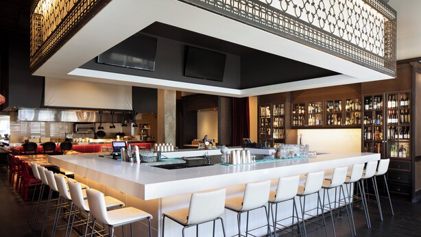A modern kitchen with a bar area, stainless steel appliances, and a wine display. - Alt Hotel Winnipeg (Winnipeg)