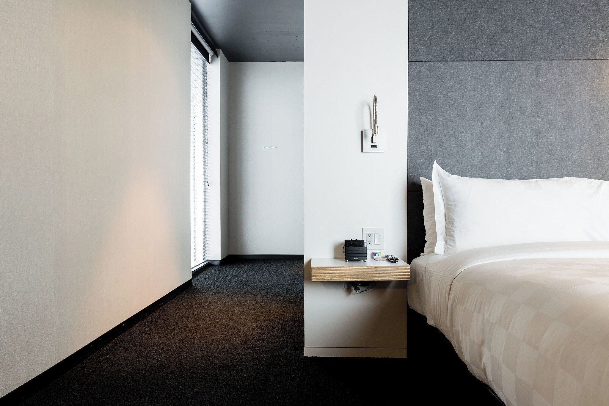 Una habitación de hotel moderna con cama, mesita de noche y toma de corriente.