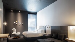 A modern hotel room with a large bed, a desk, a chair, and a sofa. - Alt Hotel Winnipeg (Winnipeg)