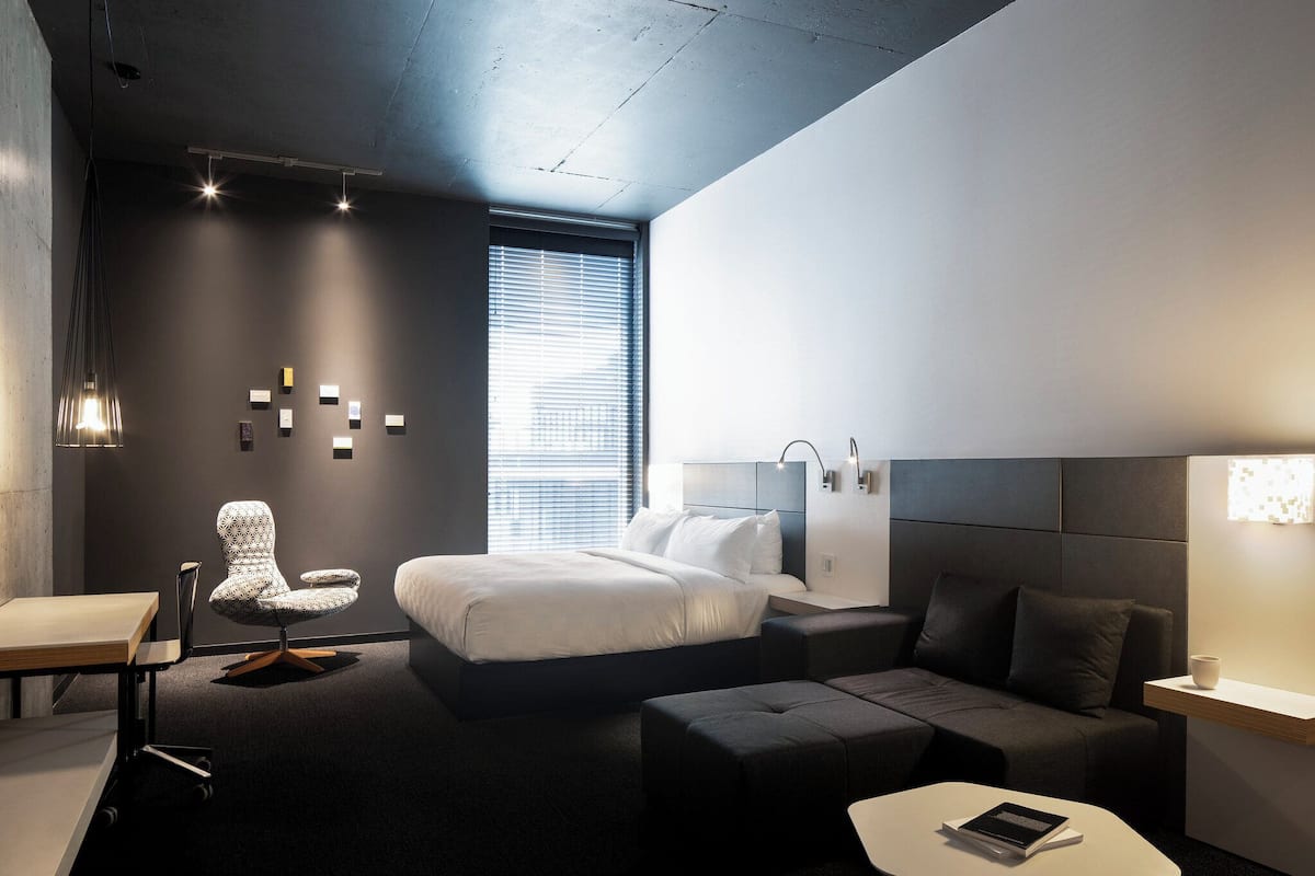 Ein modernes Hotelzimmer mit einem großen Bett, einem Schreibtisch, einem Stuhl und einer Couch.