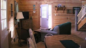 A log cabin interior with a dining table, chairs, a television, and a staircase. - Silver Queen Vacation Rental (Lake City)