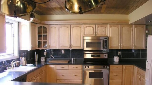 A kitchen with wooden cabinets, a black countertop, stainless steel appliances, and a window. - Lodge Vacation Rental (Lake City)