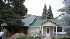 A lodge with a stone facade, a green roof, and a porch with outdoor seating. - Lodge Vacation Rental (Lake City)