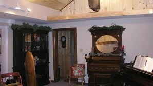 A room with a wooden ceiling, a deer head mounted on the wall, a piano, and a mirror with a decorative frame. - Lodge Vacation Rental (Lake City)