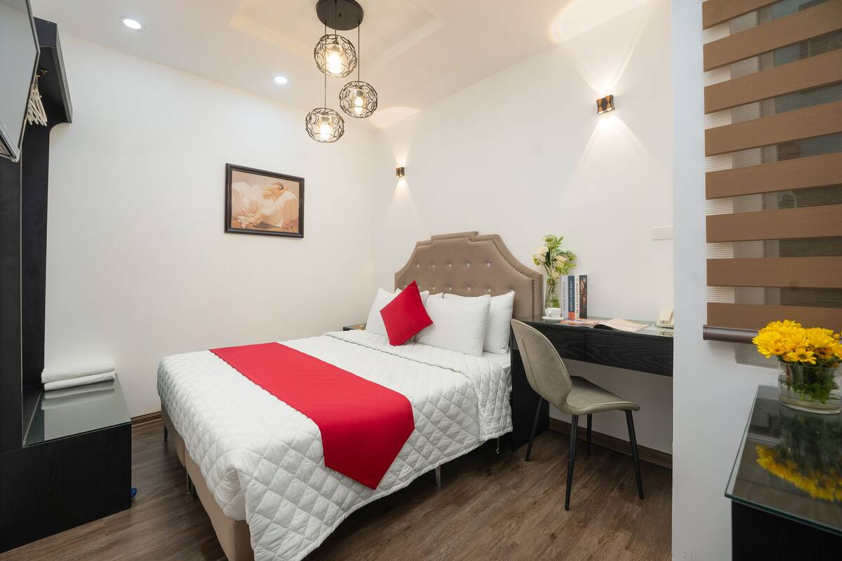 A neatly arranged bedroom with a bed, a desk, and a chair.