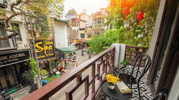 Un balcón con mesa y sillas, con vista a una calle con tiendas y un spa.
