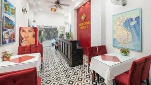Un hall de hotel con mostrador de recepción, decoración en rojo y blanco, un mapa en la pared y un suelo estampado.