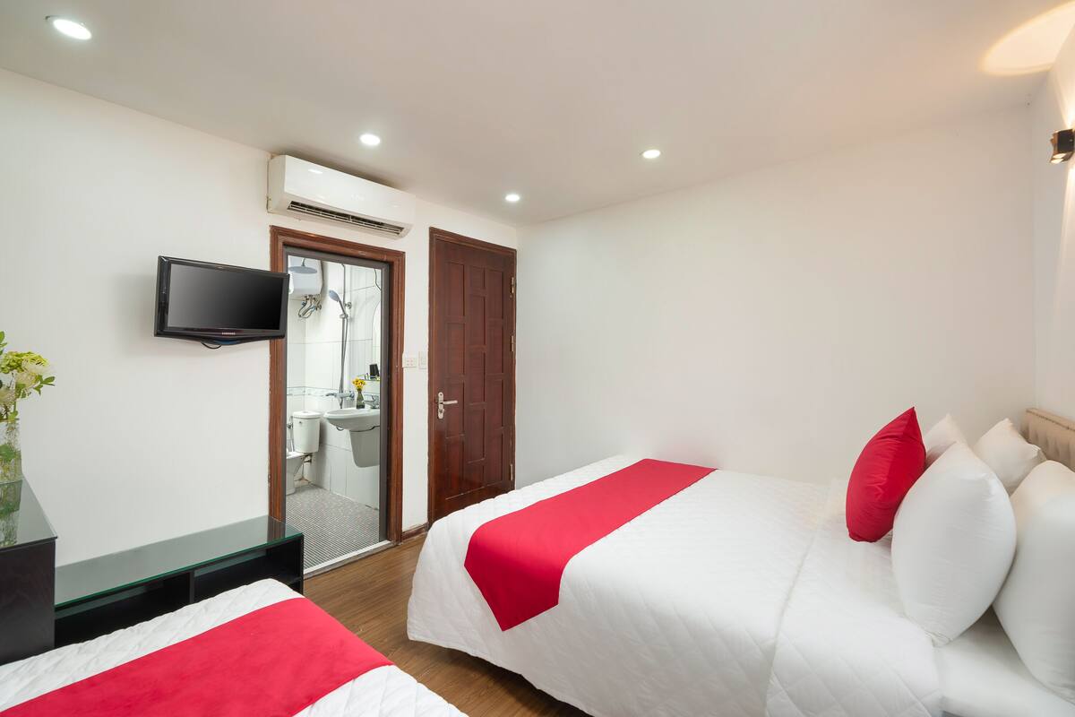 A hotel room with two beds, a TV, a mirror, and a door leading to a bathroom.