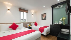 Habitación de hotel con dos camas, un televisor, un espejo y una mesita con artículos de aseo.