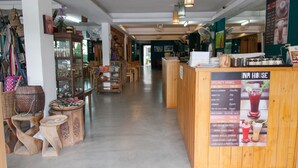 A cozy interior with wooden furniture, a central counter with a menu, and various items on shelves. - INA House (Chiang Mai)