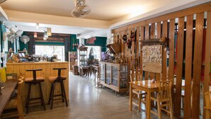 A cozy bar area with wooden stools, a counter, and a variety of items displayed on shelves and the wall. - INA House (Chiang Mai)