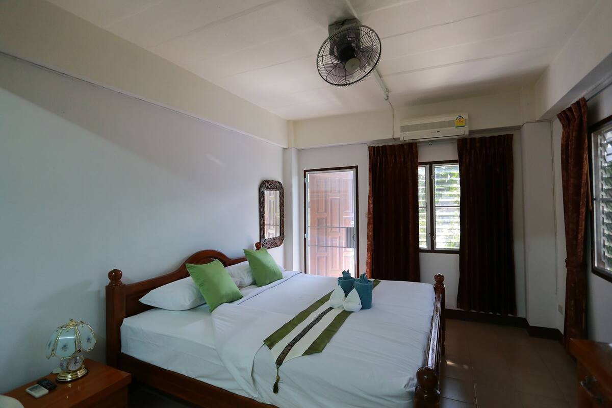 Une chambre à coucher avec un lit, une table de chevet et un ventilateur de plafond.