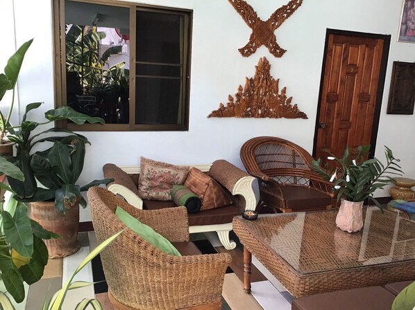 Una sala de estar acogedora con muebles de mimbre, una mesa de centro de vidrio y decoración mural.