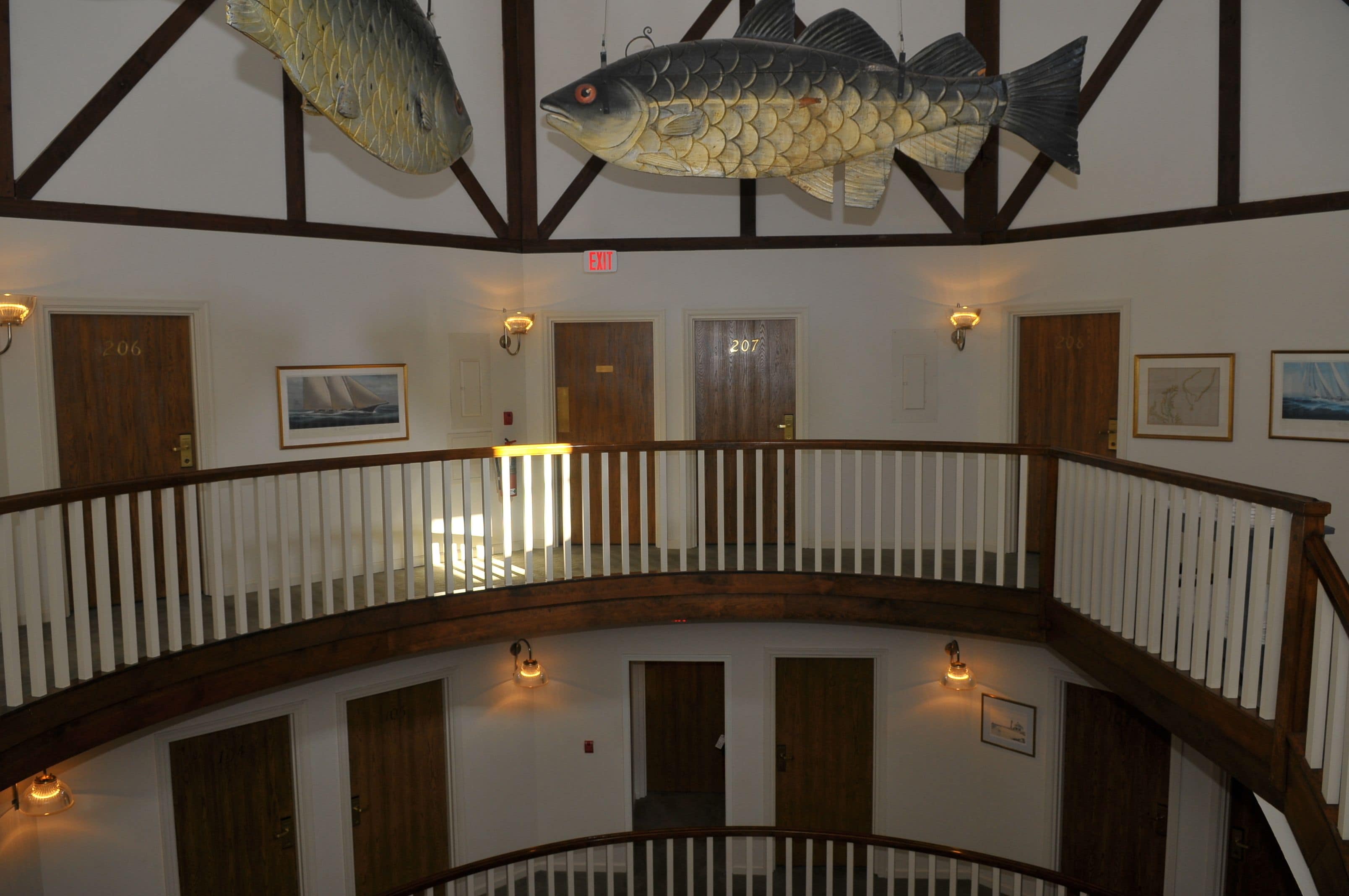 A multi-level interior with wooden railings, multiple doors, and wall-mounted light fixtures.