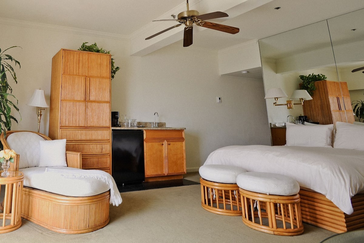A bedroom with a bed, a bedside table, a chair, a wardrobe, and a ceiling fan.