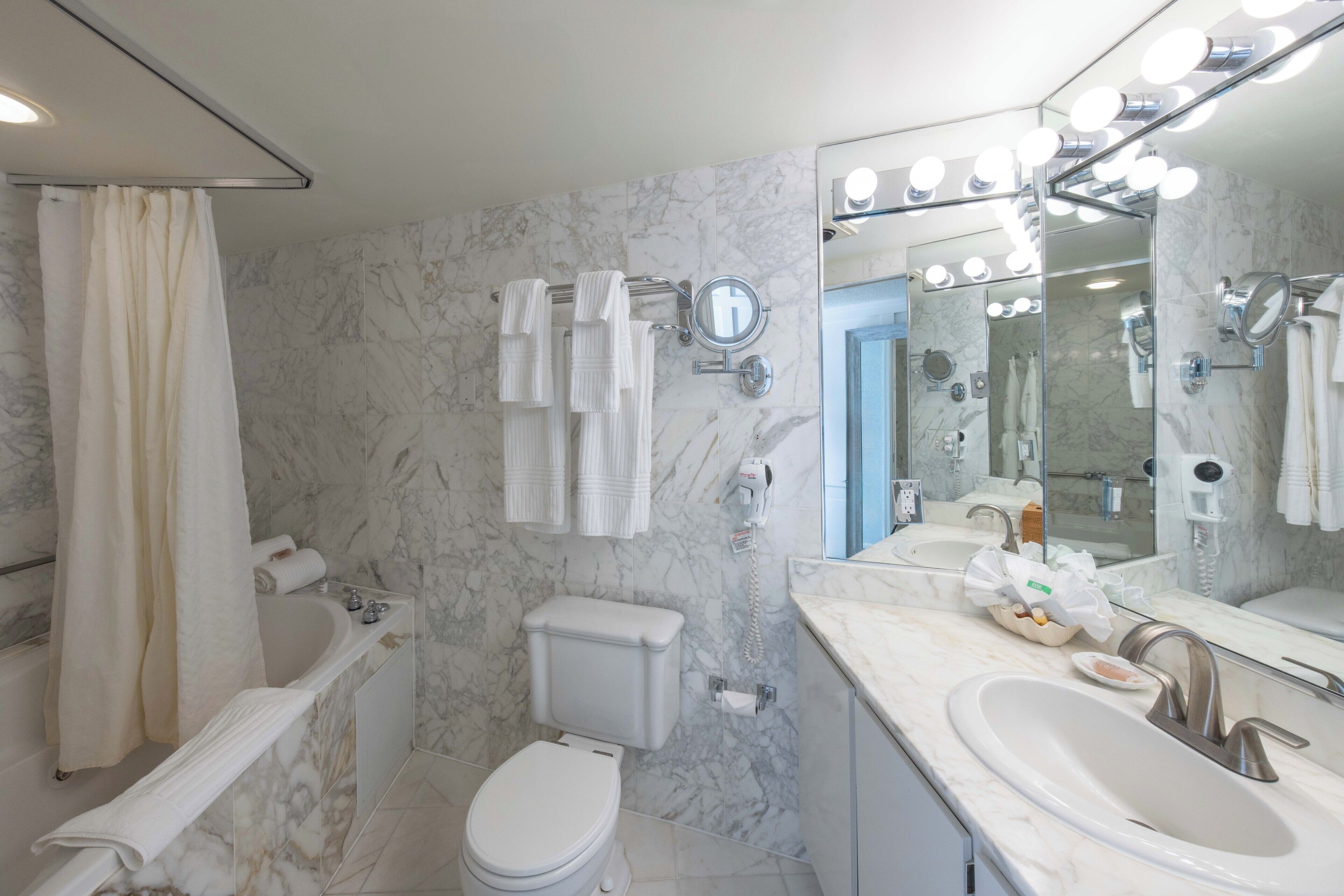 Un baño con bañera, inodoro y dos lavamanos.