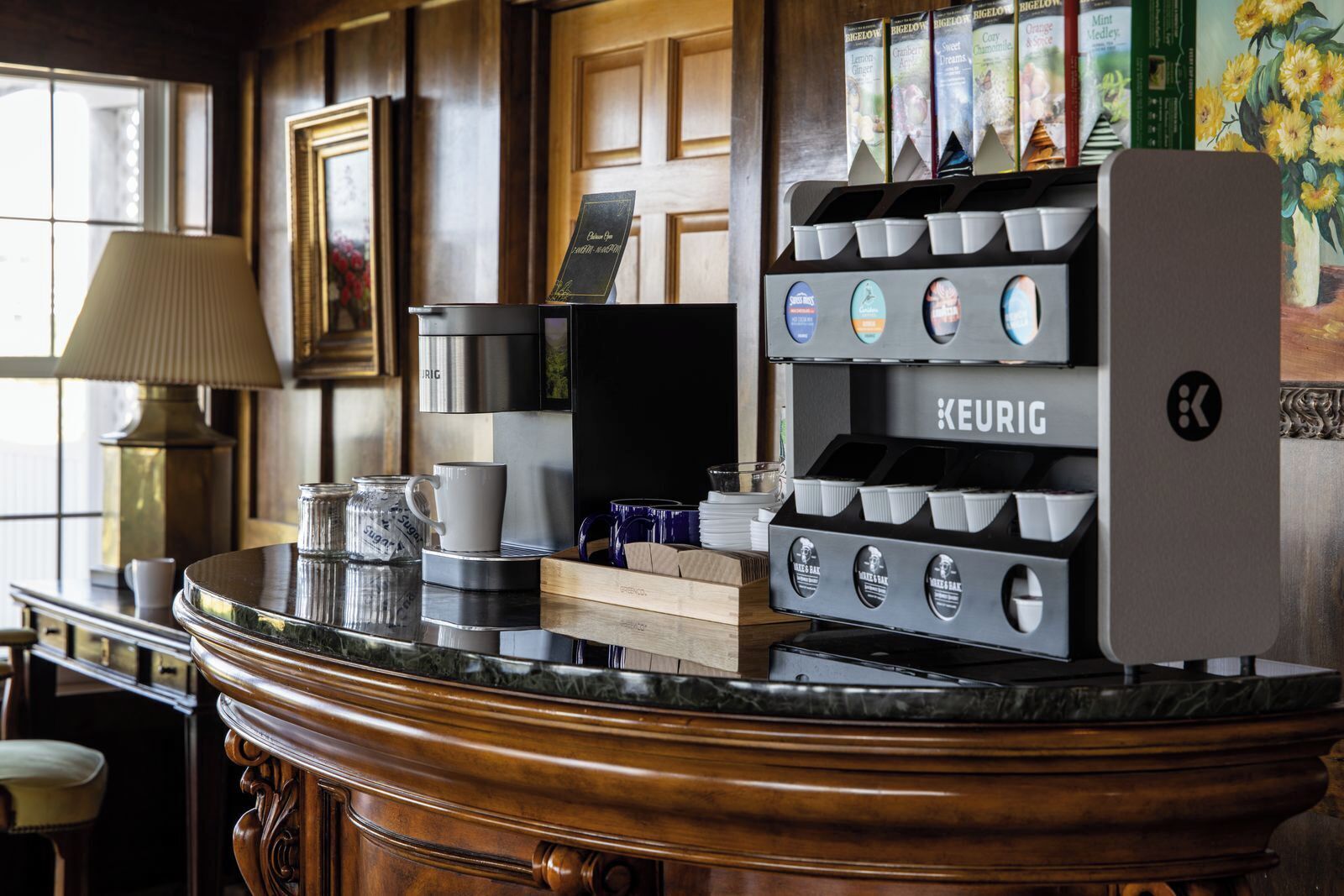 A coffee station with a Keurig machine, a coffee cup, and a sugar container.