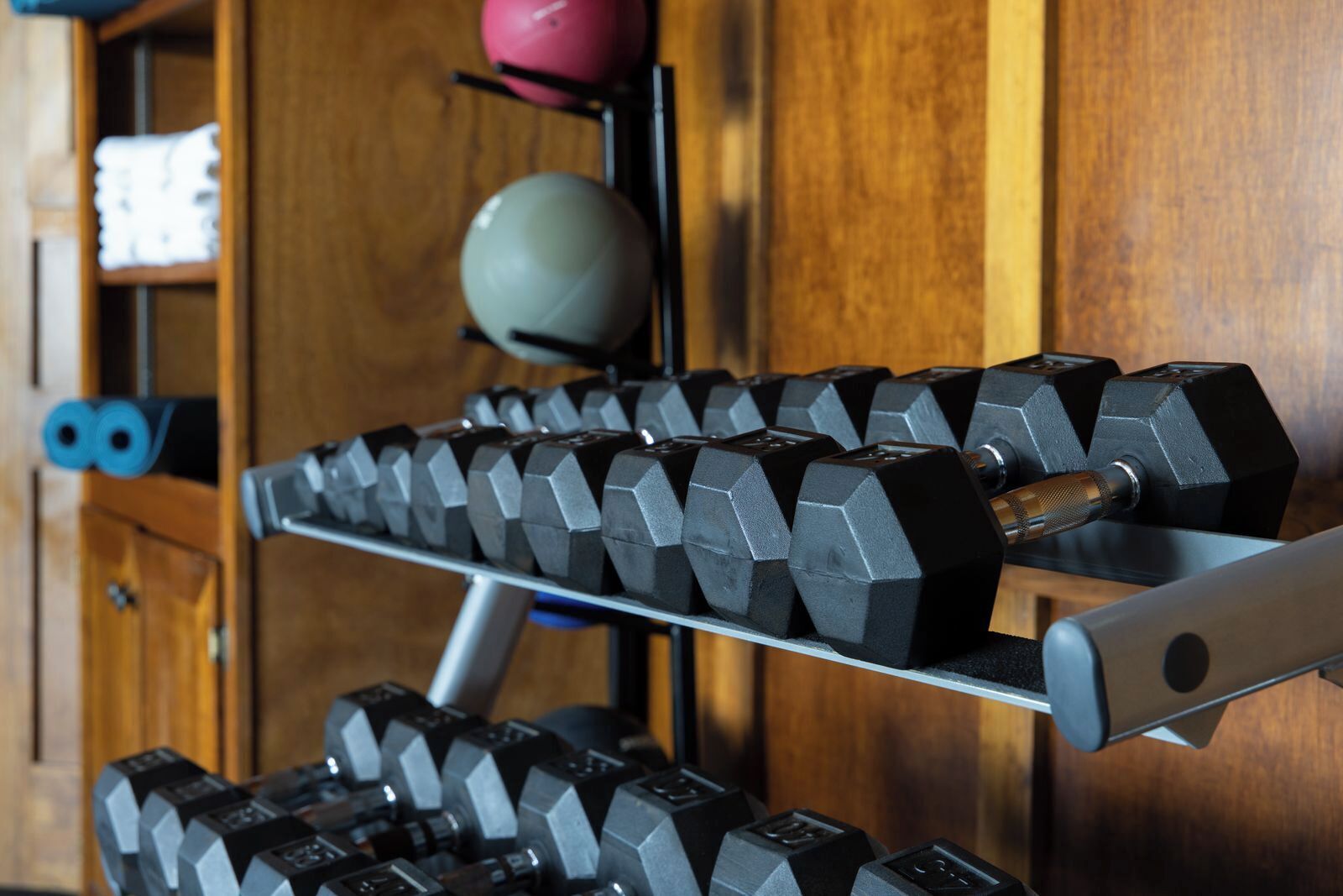 A rack of black dumbbells with a wooden background.