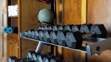 A rack of black dumbbells with a wooden background.