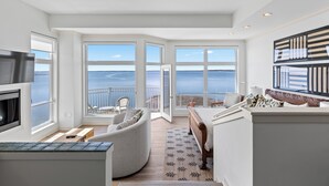 A spacious room with a large window overlooking a body of water, a built-in fireplace, and a cozy seating area.