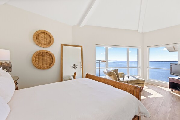 A bedroom with a large bed, a view of the sea, and a television. - The Edge at Fager's Island (Ocean City)