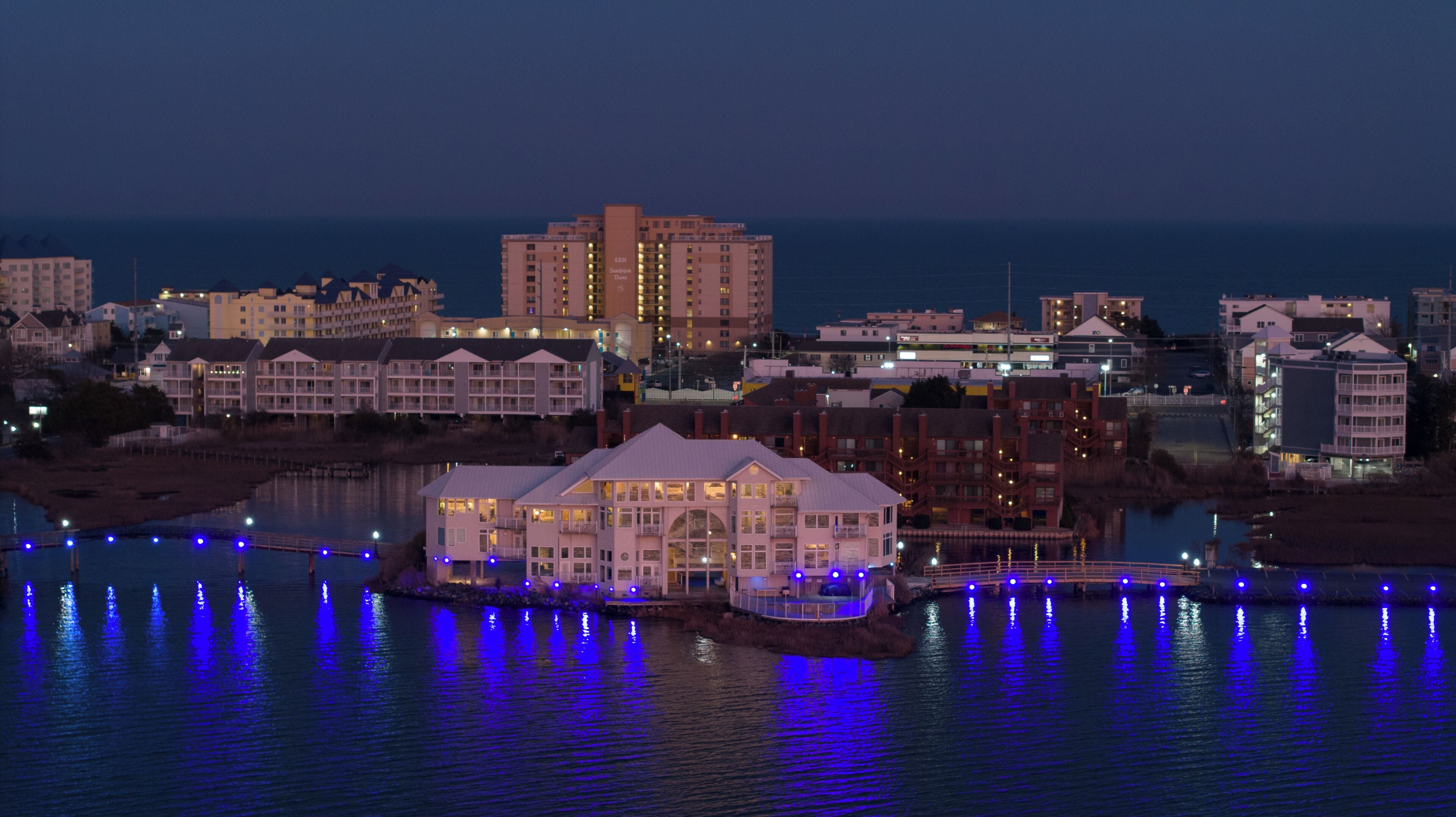 Un hôtel situé au bord de l’eau, composé de plusieurs bâtiments, doté d’un quai et donnant sur une étendue d’eau où se reflètent les lumières.