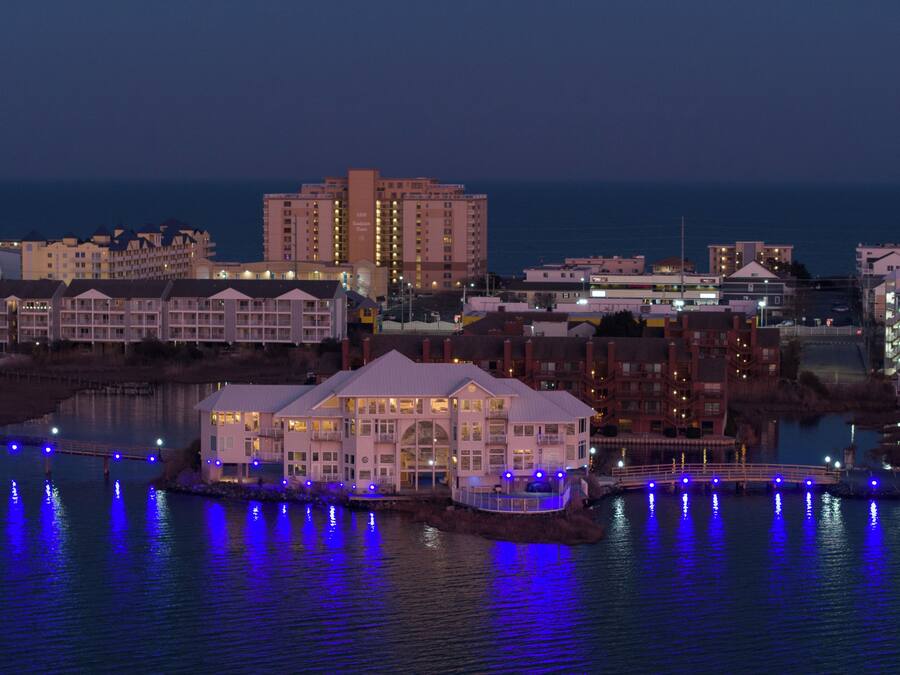 Un hôtel situé au bord de l’eau, composé de plusieurs bâtiments, doté d’un quai et donnant sur une étendue d’eau où se reflètent les lumières.