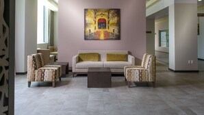 A lobby with a beige sofa, two patterned armchairs, a central coffee table, and a large abstract painting on the wall. - Hampton Inn by Hilton Zacatecas (Zacatecas)