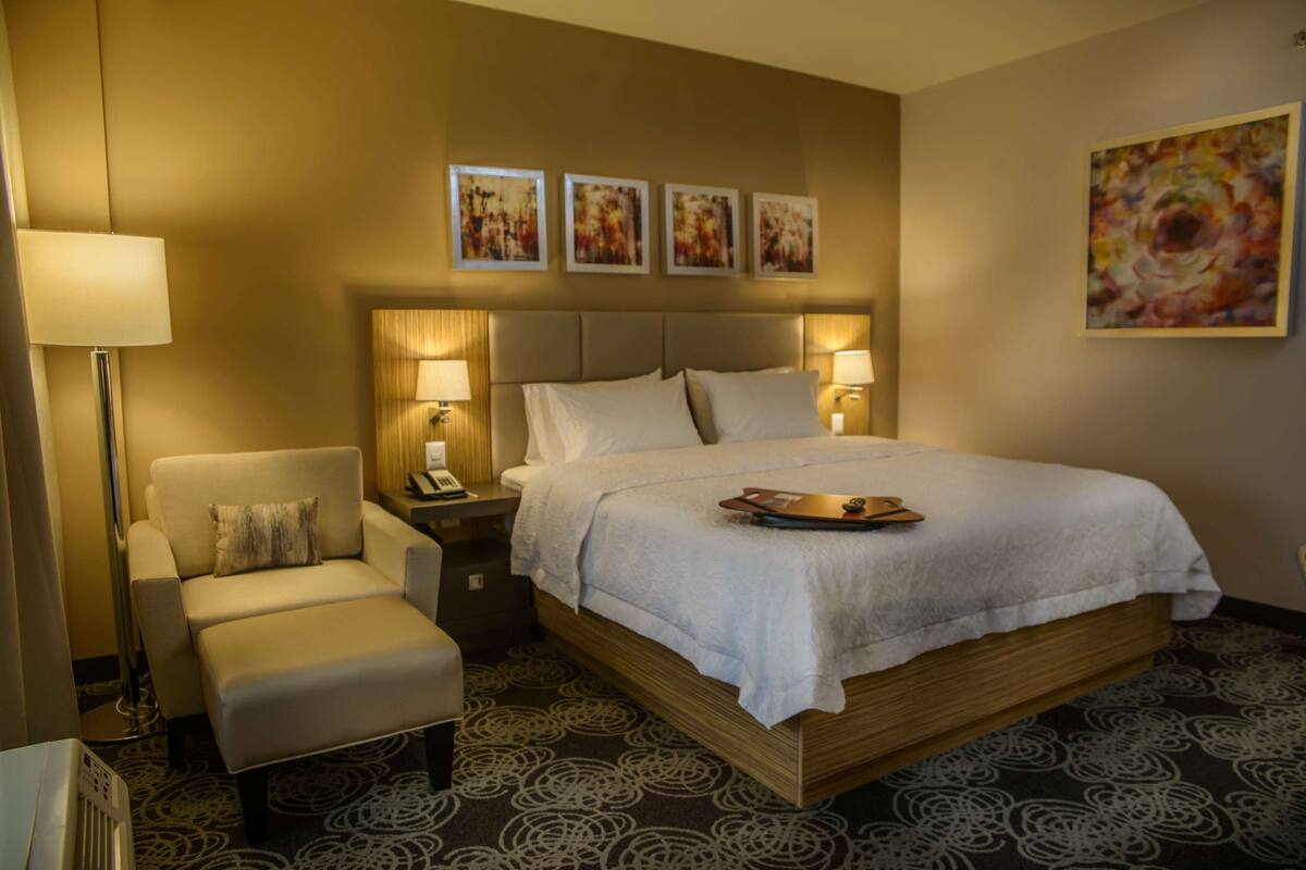 Una habitación de hotel con una cama grande, una silla, un escritorio y una lámpara.