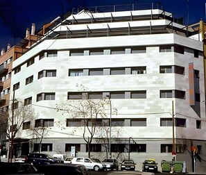 Un edificio de varios pisos con un diseño arquitectónico moderno, que cuenta con una serie de balcones y ventanas grandes.